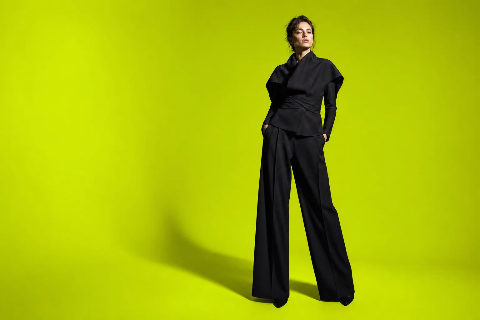 A model wearing sculptural black tailoring in a luxury fashion photoshoot